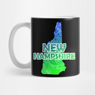 Colorful mandala art map of New Hampshire with text in blue and green Mug